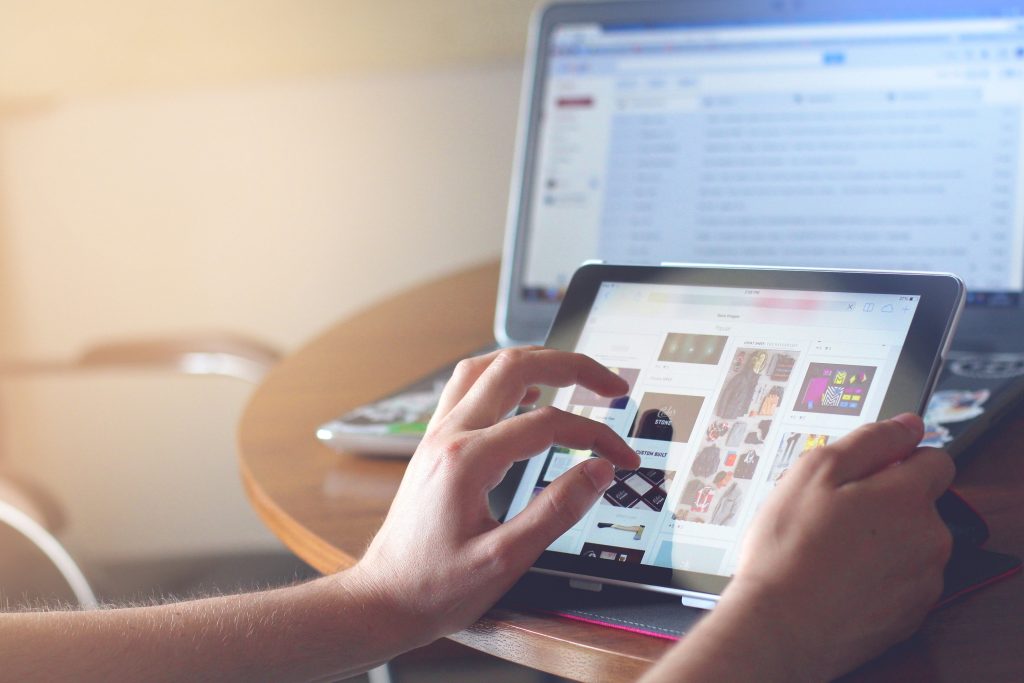 Person using tablet with laptop for digital marketing and online business in Suffolk.