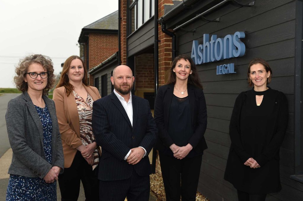 Group of professional legal team members standing outside Ashtons Legal office in Suffolk.