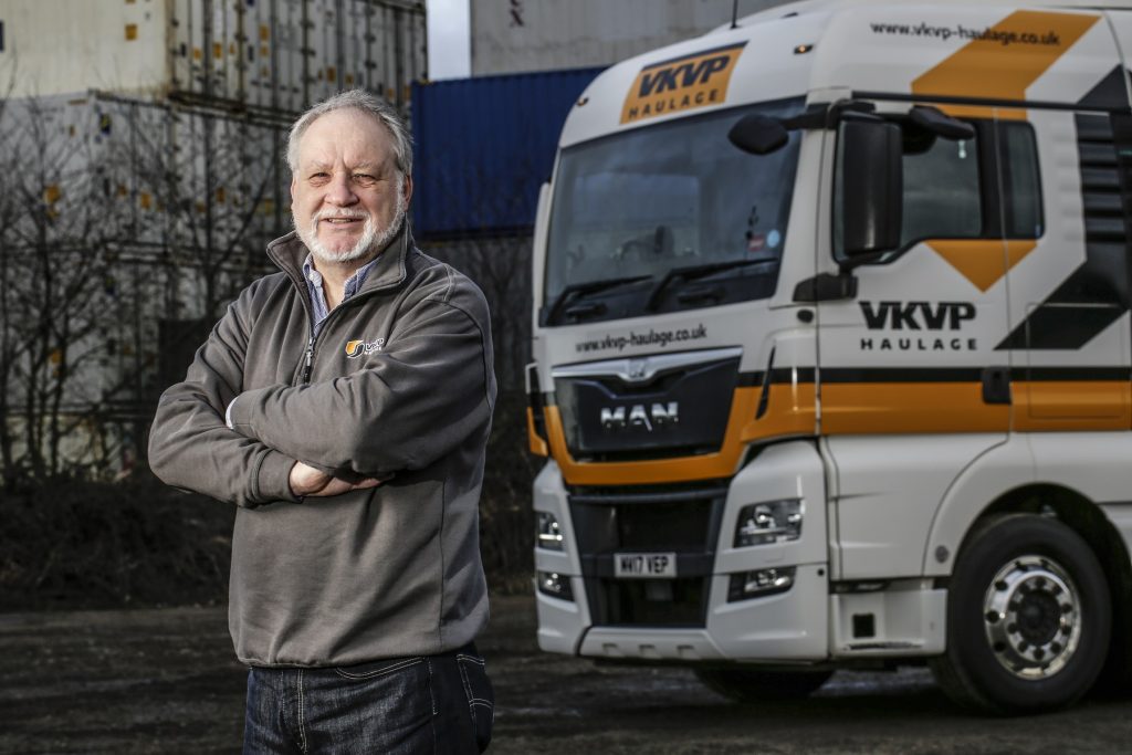Experienced man standing next to a VKVP Haulage truck in Suffolk.