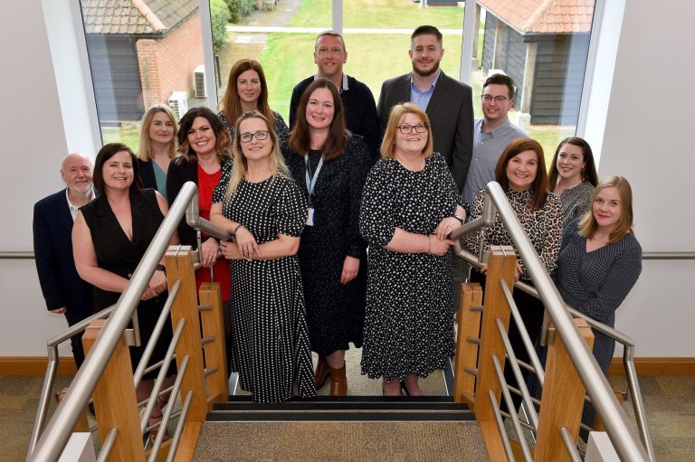 Team of diverse business professionals standing on staircase at Suffolk Business office.