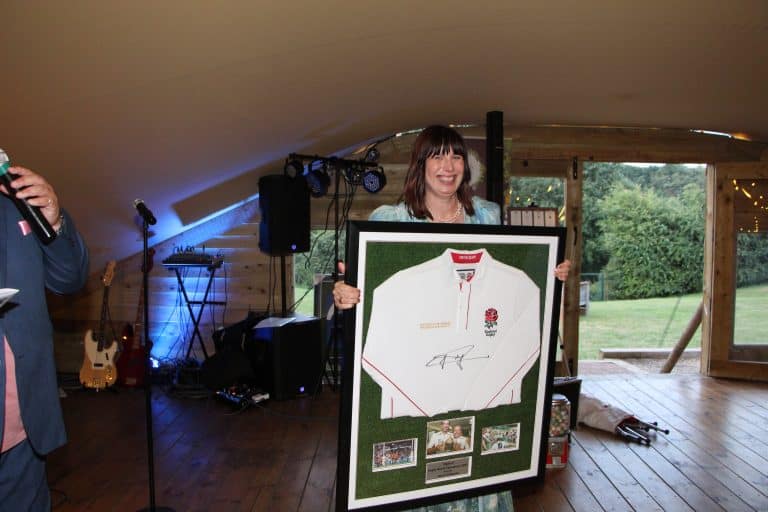 Julie Long Fundraising Manager at Suffolk Mind holding the England rugby shirt signed by Jonny Wilkinson - credit Suffolk Mind